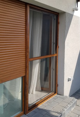 Moskitiera drzwiowa na zawiasach samodomykających, montaż z roletą zewnętrzną.