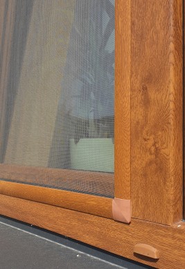 Moskitiera na oknie w bloku w kolorze złotego dębu.