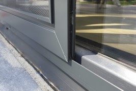 Otwarta moskitiera przesuwna na drzwi balkonowe. Skrzydło z siatką wykonaną z włókna szklanego oraz uszczelkami szczotkowymi które gwarantują szczelność pomiędzy ramą moskitiery drzwiowej a ramą okienną poruszające się po szynie jezdnej (prowadnicy).